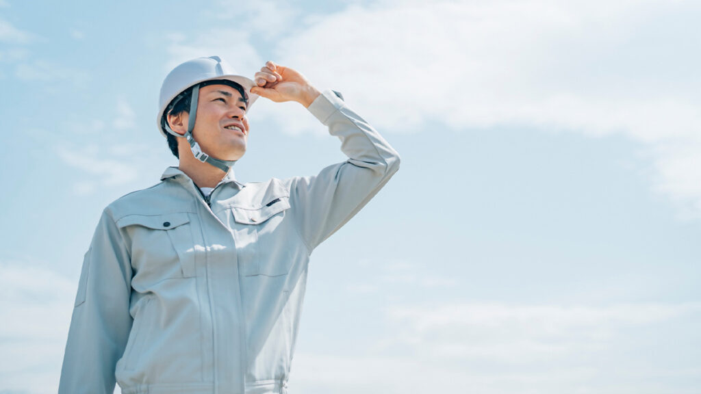 青空と作業着の男性