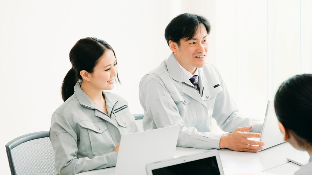 打ち合わせをしている作業着の男性と女性